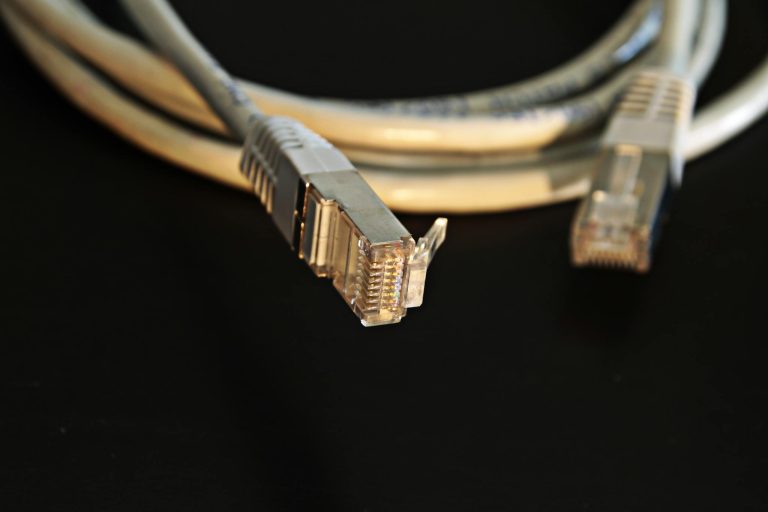 Best Cat5 cable types for home network hardwiring in the UK 3 Detailed close-up of a network Ethernet cable showing connectors on a black background.
