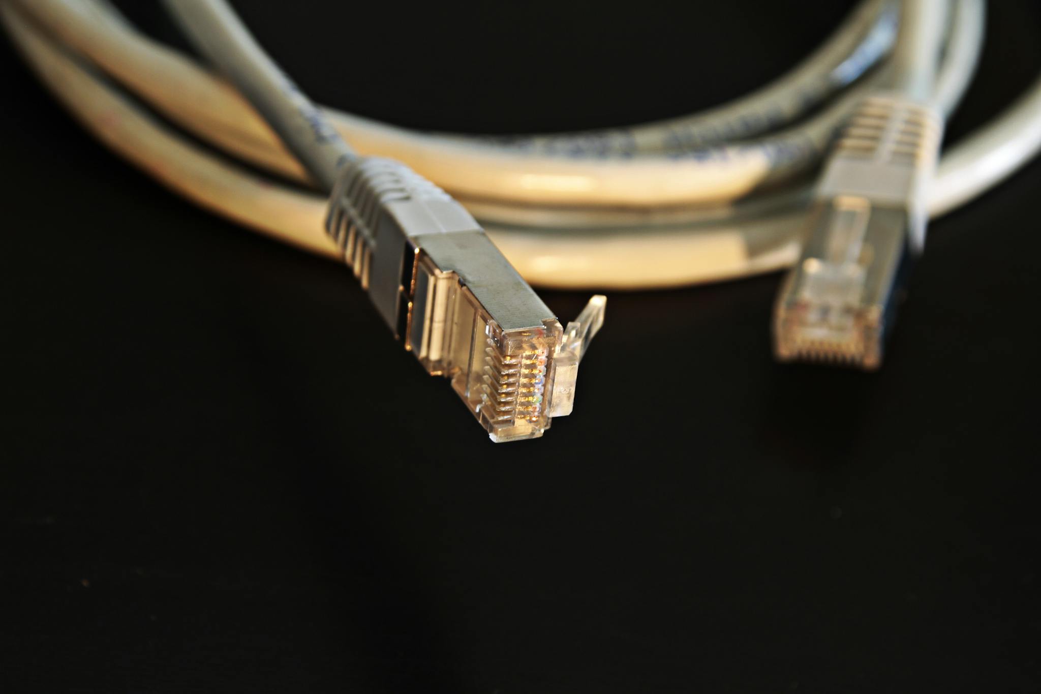 Best Cat5 cable types for home network hardwiring in the UK 1 Detailed close-up of a network Ethernet cable showing connectors on a black background.