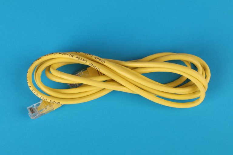 High-angle view of a yellow ethernet cable on a bright blue background.